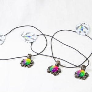 May include: Three black turtle necklaces with rainbow colored glass eyes. The necklaces are on a white background.