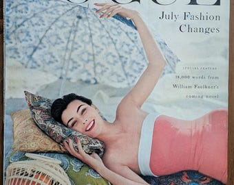 May include: Vogue magazine cover featuring a woman in a pink swimsuit, reclining on a beach with pillows and a parasol. The cover reads "July Fashion Changes" with text about William Faulkner's novel.