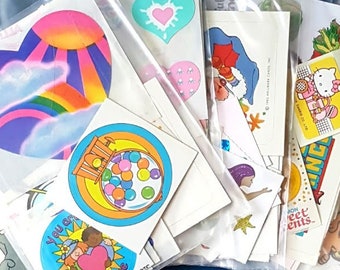 May include: A collection of vintage stickers in various colors and designs, including a rainbow heart, a cartoon character with a moon, and a sticker that says "You are sunshine".