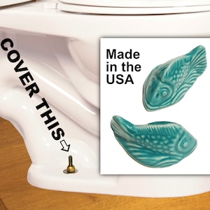 May include: Two turquoise ceramic fish, with textured scales, are displayed against a white background. The fish are labeled "Made in the USA". The image also shows a white toilet with the text "COVER THIS".