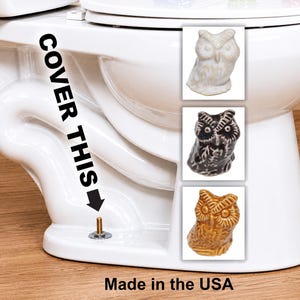 May include: White ceramic toilet with three owl figurines in white, black, and brown. Text on the toilet reads "COVER THIS" and "Made in the USA".