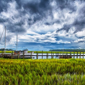 Fotografia di una vecchia barca di gamberetti ormeggiata sull'isola di Wilmington a Savannah, in Georgia. Bassa arte di campagna, paesaggio marino, nuvole di tempesta, palude.