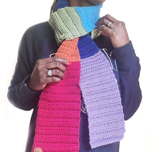 Model wearing rainbow scarf which is a long scarf.