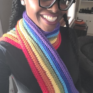 May include: A rainbow crochet scarf with red, orange, yellow, green, blue, indigo, and violet stripes.