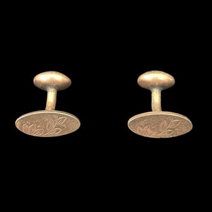 May include: A pair of silver cufflinks with an oval design featuring a floral pattern.