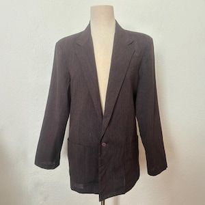May include: A brown blazer with a single button closure and two pockets. The blazer has a subtle pinstripe pattern.
