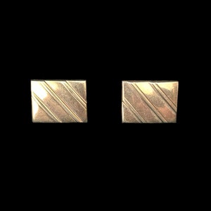 May include: A pair of silver cufflinks with a striped pattern.