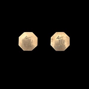 May include: A pair of gold-toned cufflinks with an octagonal shape. Each cufflink features an engraved letter "L" in a cursive font.