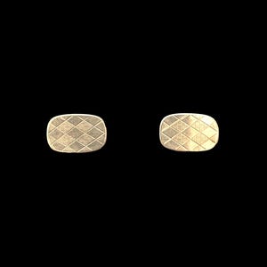 May include: A pair of gold-toned cufflinks with a geometric pattern.