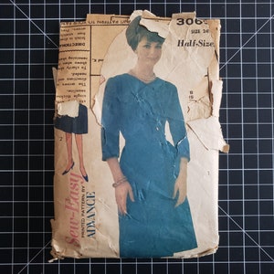 May include: Vintage sewing pattern for a dress, labeled "Sew-Easy" and "Advance", with the pattern number 306, size 24 1/2, and the words "Half-Size". The pattern shows a woman wearing a blue dress with a white collar.