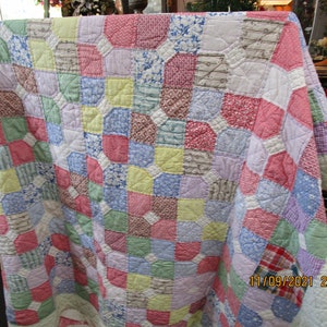 May include: A patchwork quilt featuring a repeating pattern of octagonal fabric pieces in various pastel colors including pink, blue, yellow, green, and lavender, accented with small white squares and intricate stitching, dated 11/09/2021 22:14.