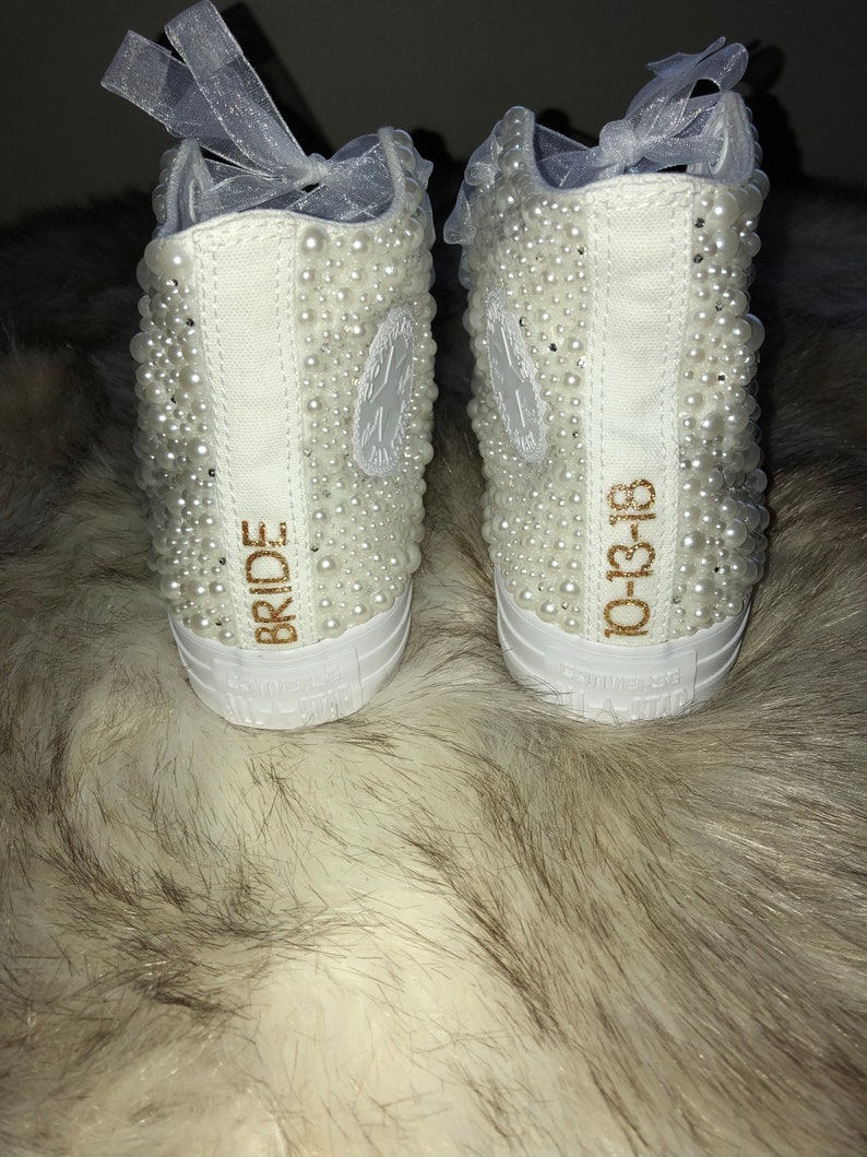 May include: White high-top sneakers with pearl embellishments. The left shoe says "BRIDE" and the right shoe says "10-13-18".