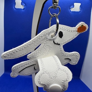 May include: White felt keychain with a stitched design of a character from the movie "The Nightmare Before Christmas". The character is holding a small orange pumpkin. The keychain has a silver metal ring and a silver metal clasp.