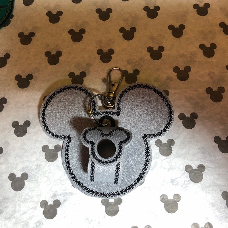 May include: A gray felt Mickey Mouse keychain with black stitching and a silver key ring.