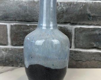 Zelfgemaakte keramische fles: zwart en lichtblauw glazuur, op een wiel geworpen decoratief aardewerk, ambachtelijk interieur.