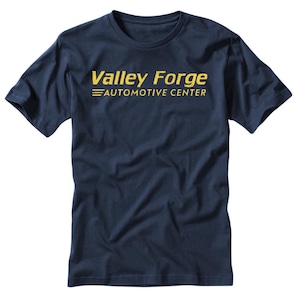 May include: Navy blue t-shirt with the text "Valley Forge Automotive Center" in yellow. The text is centered on the front of the shirt. The shirt has short sleeves and a crew neck.