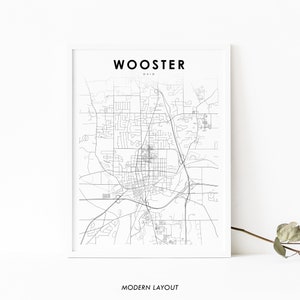 May include: A black and white line art map of Wooster, Ohio. The map is printed on white paper and framed in a white frame. The text "WOOSTER OHIO" is printed at the top of the map. The text "MODERN LAYOUT" is printed at the bottom of the map.