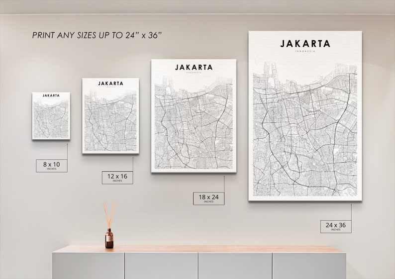 May include: Four different sizes of a black and white map print of Jakarta, Indonesia. The prints are displayed on a white wall with a wooden shelf underneath. The sizes are 8x10 inches, 12x16 inches, 18x24 inches, and 24x36 inches.