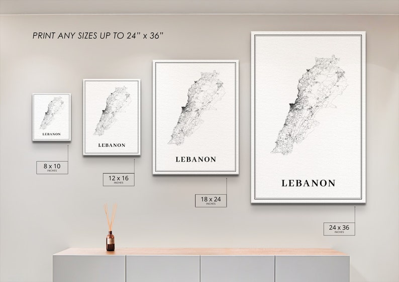 May include: Four framed prints of a black and white map of Lebanon, with the word "Lebanon" printed below each map. The prints are shown in different sizes: 8x10 inches, 12x16 inches, 18x24 inches, and 24x36 inches. The prints are displayed on a white wall with a wooden shelf below.