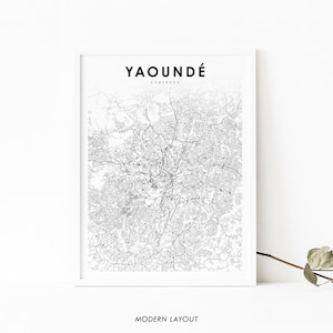 May include: A black and white city map print of Yaoundé, Cameroon. The map shows the city's streets and roads. The title "YAOUNDÉ" and "CAMEROON" are printed in black at the top of the map. The words "MODERN LAYOUT" are printed in black at the bottom of the map.