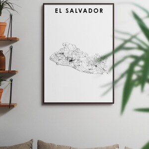 K&ouml;nnte beinhalten: Ein Schwarz-Wei&szlig;-Linienkunst-Druck von El Salvador, gerahmt in einem schwarzen Rahmen. Der Druck h&auml;ngt an einer wei&szlig;en Wand &uuml;ber einem Sofa mit beigen Kissen.