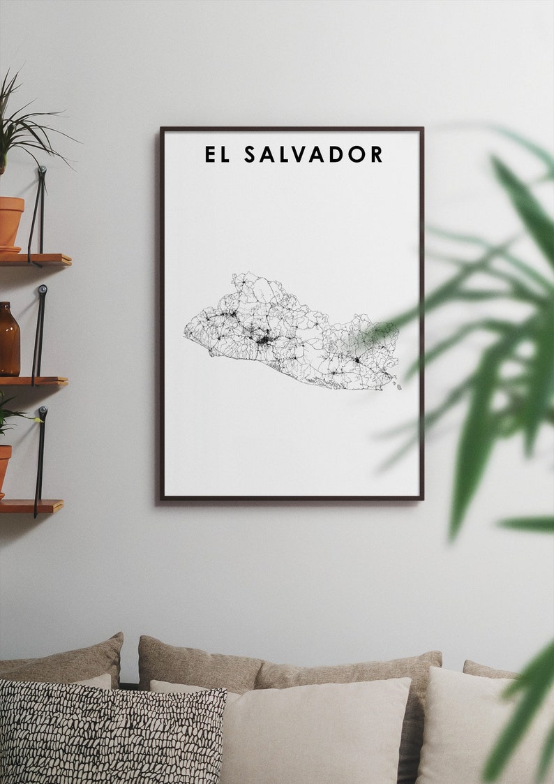 K&ouml;nnte beinhalten: Ein Schwarz-Wei&szlig;-Linienkunst-Druck von El Salvador, gerahmt in einem schwarzen Rahmen. Der Druck h&auml;ngt an einer wei&szlig;en Wand &uuml;ber einem Sofa mit beigen Kissen.