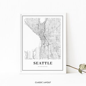May include: Black and white map print of Seattle, Washington with the city name and state printed below the map. The map shows the streets and roads of the city. The print is framed in a white frame.