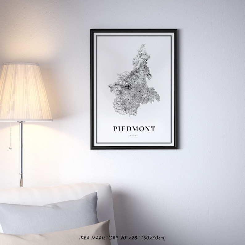 May include: A black and white map print of the Piedmont region of Italy in a black frame. The map is a detailed illustration of the region's roads and cities. The print is labeled "Piedmont, Italy" and is 20 inches by 28 inches (50x70 cm).