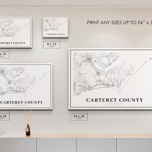 May include: Four framed black and white prints of a map of Carteret County, North Carolina. The prints are displayed on a white wall with a light brown wooden shelf below. The prints are available in four sizes: 8x10 inches, 12x16 inches, 18x24 inches, and 24x36 inches. The text 'PRINT ANY SIZES UP TO 24' x 36' is displayed above the prints.