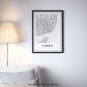 May include: Black and white map print of Lisbon, Portugal, in a black frame. The map shows the city streets and the Tagus River. The print is 20 inches by 28 inches (50 cm by 70 cm).