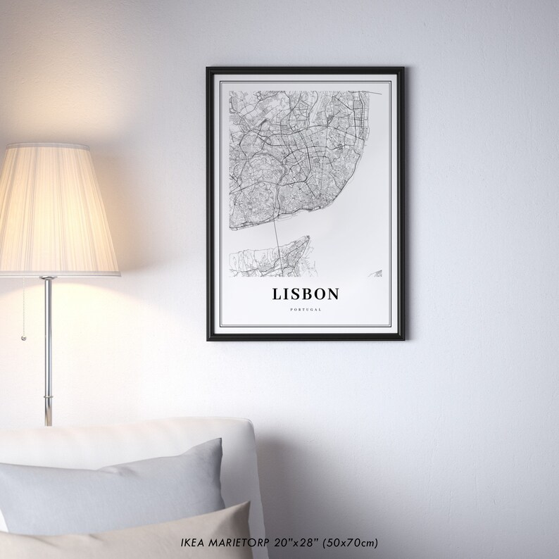 May include: Black and white map print of Lisbon, Portugal, in a black frame. The map shows the city streets and the Tagus River. The print is 20 inches by 28 inches (50 cm by 70 cm).