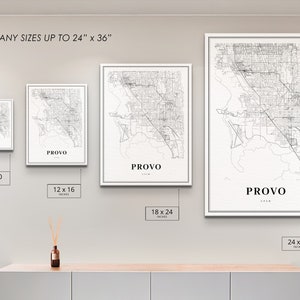 May include: Four different sizes of a black and white city map print of Provo, Utah. The prints are displayed on a white wall with a wooden shelf underneath. The text "PRINT ANY SIZES UP TO 24" x 36"" is at the top of the image. The sizes of the prints are 8 x 10 inches, 12 x 16 inches, 18 x 24 inches, and 24 x 36 inches.