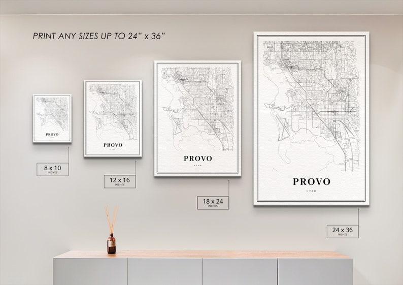 May include: Four different sizes of a black and white city map print of Provo, Utah. The prints are displayed on a white wall with a wooden shelf underneath. The text "PRINT ANY SIZES UP TO 24" x 36"" is at the top of the image. The sizes of the prints are 8 x 10 inches, 12 x 16 inches, 18 x 24 inches, and 24 x 36 inches.