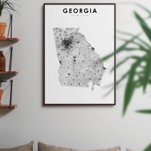 May include: A black and white print of a map of Georgia, United States. The map is framed in a black frame and is hanging on a white wall.