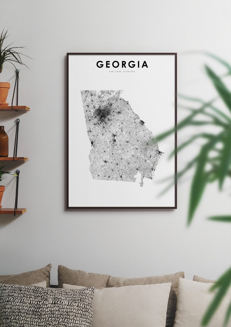 May include: A black and white print of a map of Georgia, United States. The map is framed in a black frame and is hanging on a white wall.