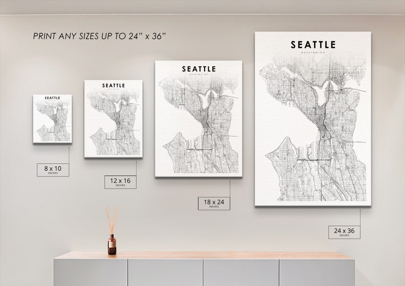 May include: A white wall with four different sized prints of a black and white map of Seattle, Washington. The prints are 8x10 inches, 12x16 inches, 18x24 inches, and 24x36 inches.