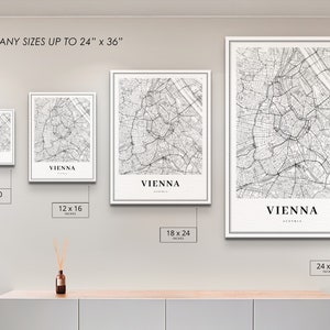 Op de afbeelding: Vier ingelijste zwart-wit kaarten van Wenen, Oostenrijk, die de straten van de stad laten zien. De lijsten zijn wit en de kaarten zijn gedrukt op wit papier. De kaarten worden weergegeven op een witte muur met een houten plank eronder. De kaarten zijn verkrijgbaar in vier formaten: 8x10 inch, 12x16 inch, 18x24 inch en 24x36 inch.