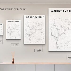 Pu&ograve; includere: Quattro stampe incorniciate di una mappa del Monte Everest, Nepal, in diverse dimensioni: 8x10 pollici, 12x16 pollici, 18x24 pollici e 24x36 pollici. Le stampe sono appese a una parete bianca sopra uno scaffale in legno chiaro.