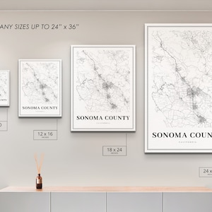 May include: Four different sizes of a black and white map print of Sonoma County, California. The prints are framed in white and are displayed on a light gray wall. The sizes are 8x10 inches, 12x16 inches, 18x24 inches, and 24x36 inches.
