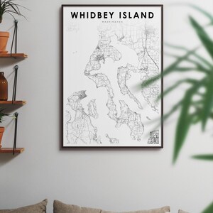 May include: A black and white map print of Whidbey Island, Washington, in a black frame. The map shows the island's roads, waterways, and land features.