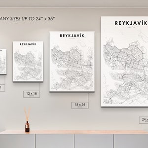 May include: A white wall with four different sizes of black and white city maps of Reykjavik, Iceland. The maps are framed and hanging on the wall. The sizes are 8x10 inches, 12x16 inches, 18x24 inches, and 24x36 inches.