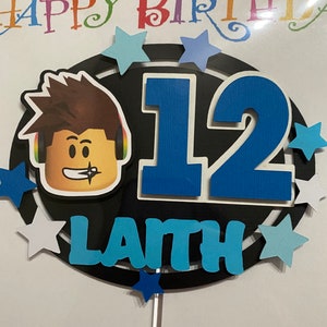 Pode incluir: Um topo de bolo preto e azul com um personagem de desenho animado, o n&uacute;mero 12 e o nome "Lanth". O topo &eacute; decorado com estrelas brancas e azuis.