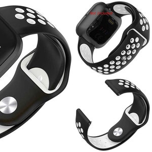 Peut inclure: Bracelet de montre en silicone noir et blanc avec un design perfor&eacute;. Le bracelet est compatible avec les montres intelligentes Fitbit Versa 3 et Sense.