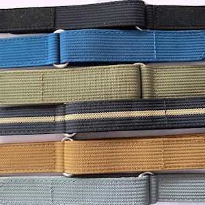 May include: A collection of six adjustable watch straps made of woven nylon fabric in various colors including black, blue, olive green, a black strap with a tan center stripe, tan, and gray, each featuring a silver-toned metal D-ring and hook-and-loop closure.