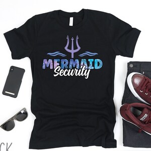 May include: Black t-shirt with a mermaid security graphic. The graphic features a trident, waves, and the text "Mermaid Security".
