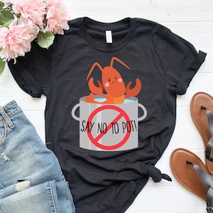 May include: Black t-shirt featuring a cartoon lobster in a pot with the text "Say No To Pot!" printed on it.