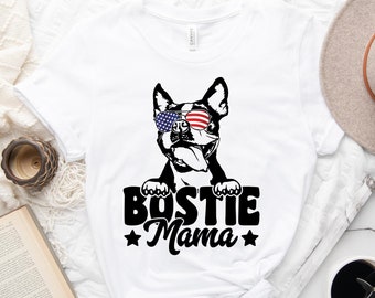 May include: White t-shirt with a black and white graphic of a Boston Terrier wearing American flag sunglasses and the text "Bostie Mama" with stars on either side.