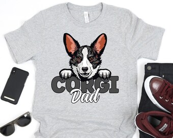 May include: A gray t-shirt with a black and white corgi peeking over the top. The text "Corgi Dad" is printed below the dog.