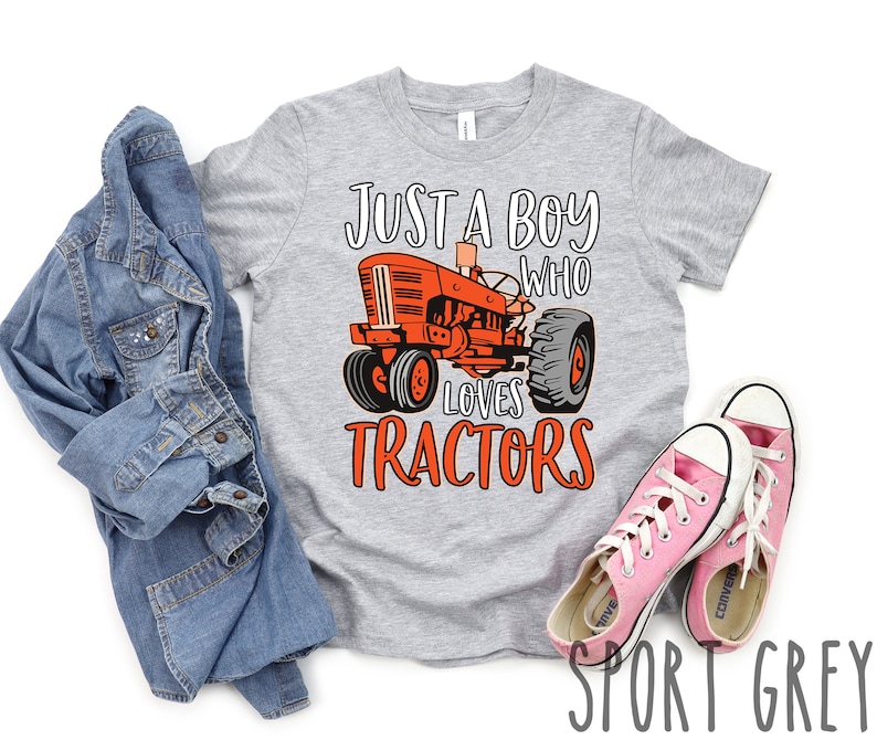 May include: A gray t-shirt with the text "Just a boy who loves tractors" in orange. A cartoon image of a red tractor is in the center of the shirt.