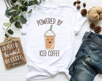 May include: White t-shirt with the text "Powered by Iced Coffee" and a cartoon iced coffee cup with a smiling face.